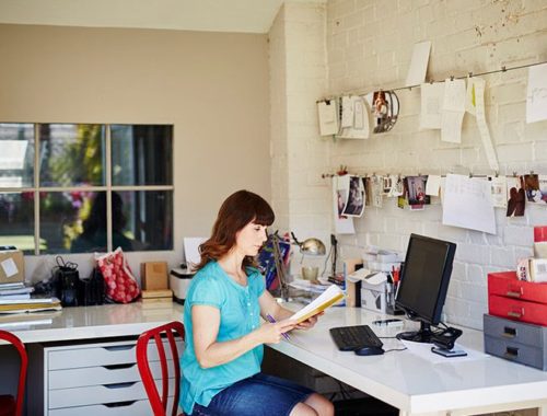 Donna in telelavoro davanti al suo notebook e al suo computer accanto a una stampante multifunzione a colori Xerox® C315