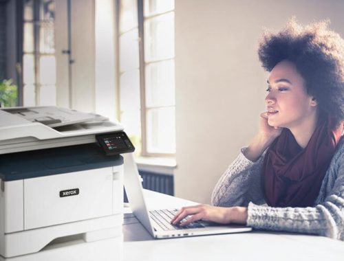 Giovane donna che lavora al suo computer accanto a una stampante multifunzione Xerox® B315.