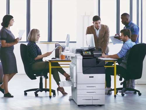Squadra al lavoro in un ufficio con carta stampata e la stampante multifunzione a colori Xerox® VersaLink® serie C7100