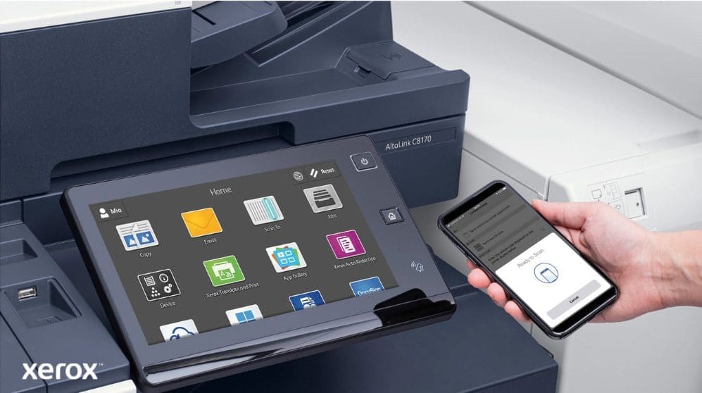 Xerox® ConnectKey®: stampa e scansione mobile Primo piano della mano di una persona che tiene uno smartphone, connesso in modalità wireless al pannello di controllo touchscreen di una stampante multifunzione Xerox, che mette in mostra le funzionalità di stampa e scansione mobile senza interruzioni di Xerox ConnectKey.