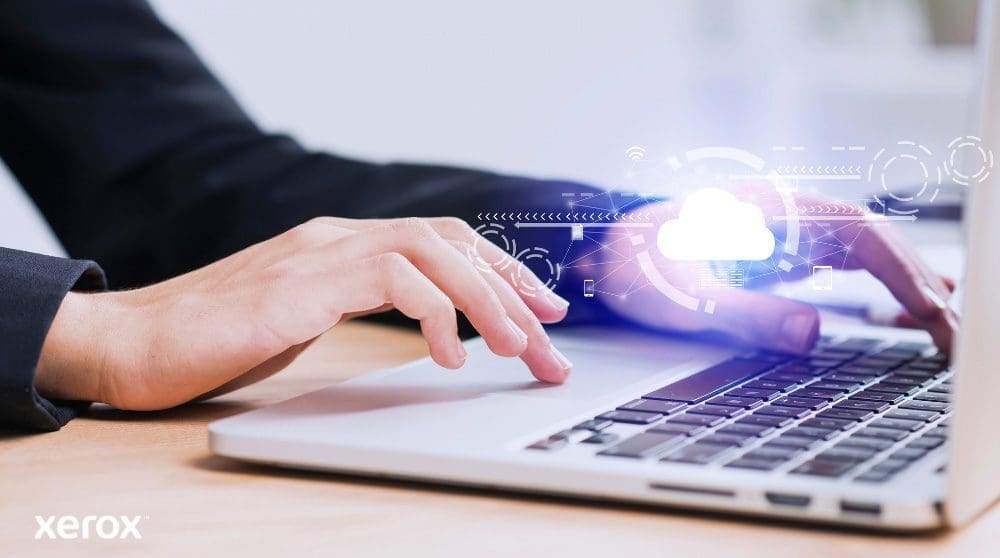 Xerox® Workplace Cloud e Suite: Connettività cloud Sono raffigurate le mani di una persona che digita sulla tastiera di un computer portatile, con un'icona luminosa a forma di nuvola e connessioni di rete sovrapposte all'immagine, a simboleggiare la connettività cloud e i flussi di lavoro digitali.